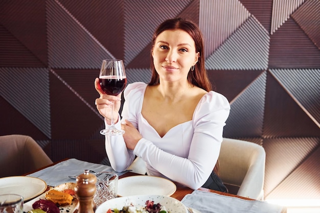 Woman with wine and food indoors of new modern luxury
restaurant