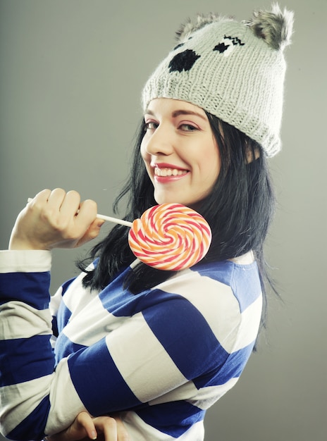 Woman with winter hat holding big lollipop