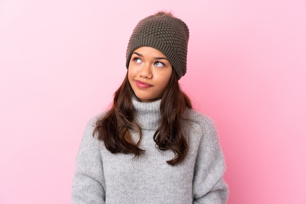 Woman with winter hat over isolated pink wall