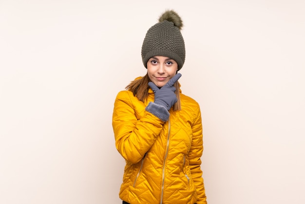 Woman with winter hat over isolated wall thinking an idea