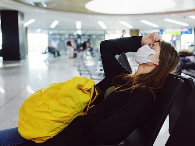 A woman with a yellow backpack sits at the airport long waiting for a flight High quality photo