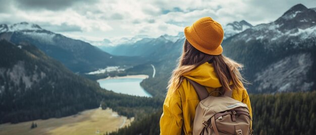 黄色い帽子をかぶった女性が町と山の景色を背景に山を見ています