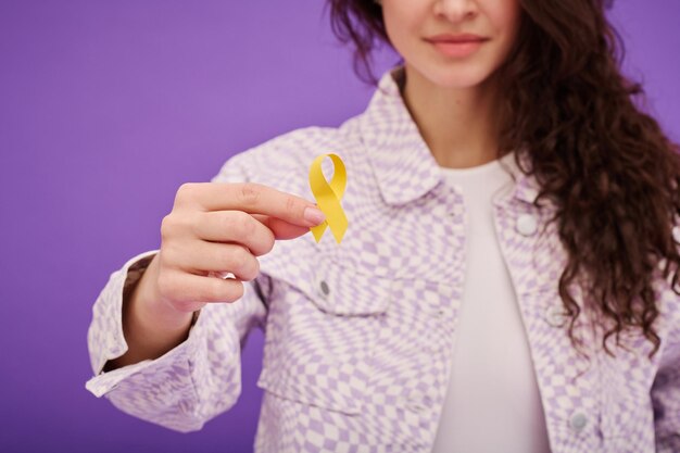 Woman with yellow ribbon on color background