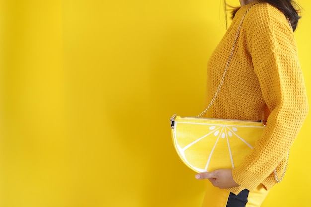 Woman with yellowish fashion style hold lemon shaped bag with\
copy space creative yellow mood