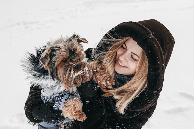 Woman with yorkshire terrier outdoors at winter happy and having fun.