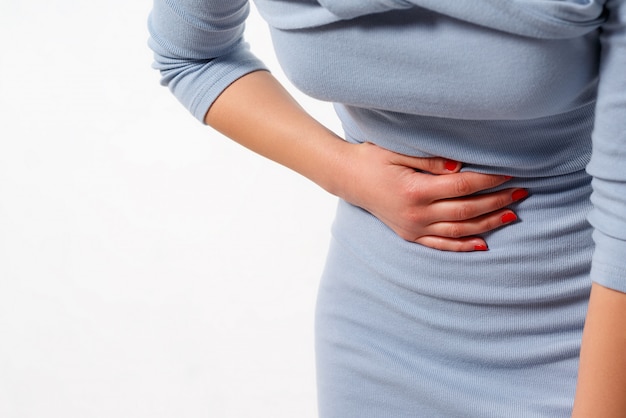 woman woman is having stomach ache on white wall.