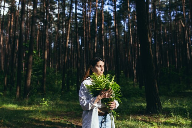 森の中の女性がシダの花束を抱きしめ、若い活動家が森を守る