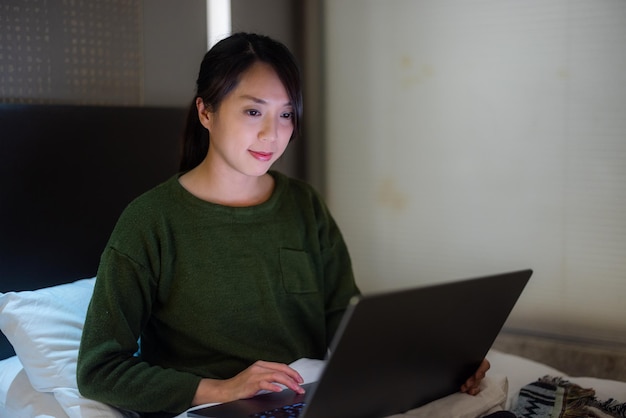 Woman work on laptop and sit on bed