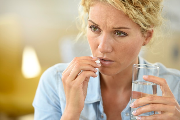 Photo woman at work taking pill to ease headache