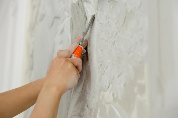 Woman at work with chisel tool carves basrelief pattern on wall