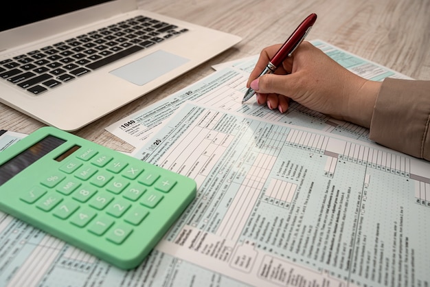 Фото Женщина работает с налоговой формой сша 1040 и ноутбуком калькулятора в офисе. концепция бухгалтерского учета