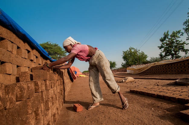 Woman worker arranges bricks for the next process in brick factory