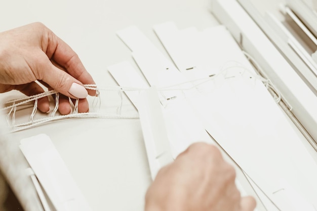 Woman worker assembles aluminum blinds at the factory by hand