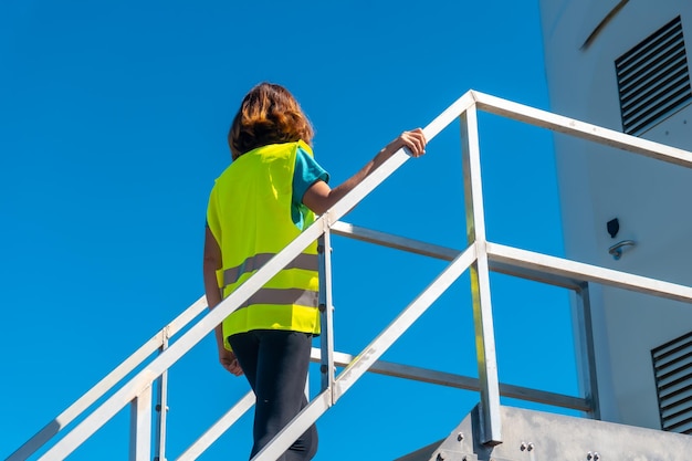 Lavoratrice in un parco eolico energia verde salendo le scale della revisione tecnica della turbina