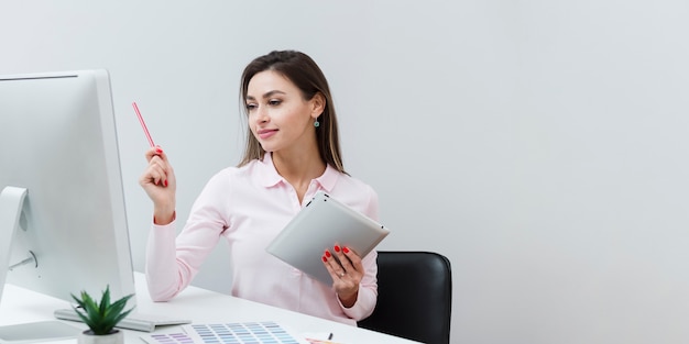 Woman working at desk while holding tablet