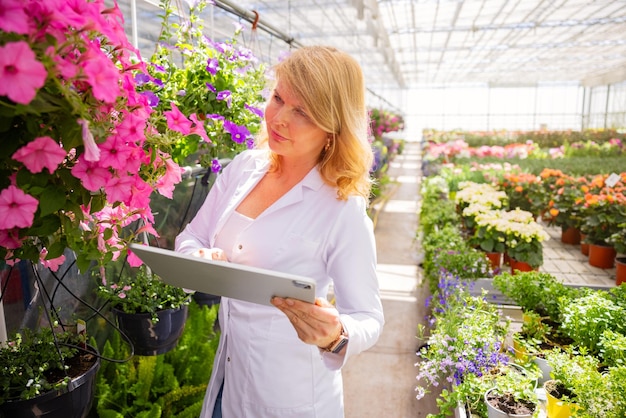 Woman working in greenhouse and using tablet computer