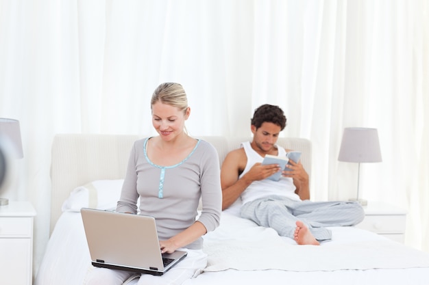 Woman working on her laptop while her husband is reading 