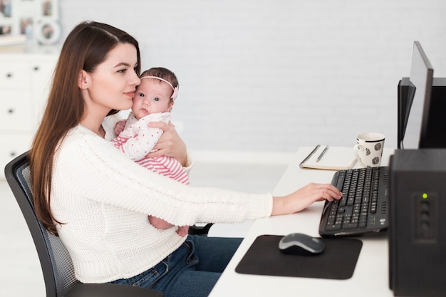 Foto donna che lavora e che tiene il bambino