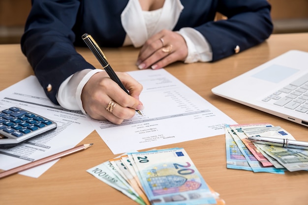 Woman working at home buget with laptop and account euro bill