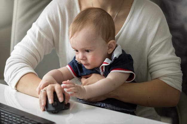 Woman working at home office and taking care of her baby son