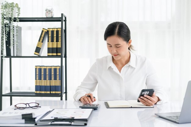 Фото Женщина, работающая в офисе с документами и документами на ноутбуке, рассчитывает финансовые показатели