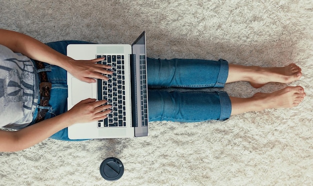 Woman working on a laptop Female using a laptop sitting on floor searching web browsing information