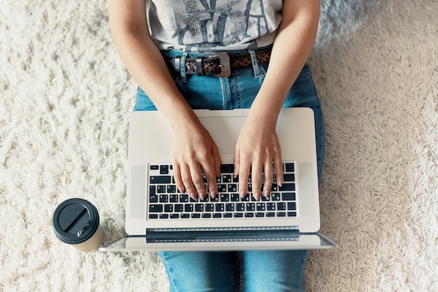 Woman working on a laptop Female using a laptop sitting on floor searching web