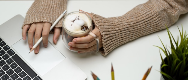 Photo woman working on a laptop and holding a cup of coffee