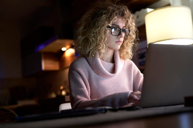 Woman working on laptop late at home