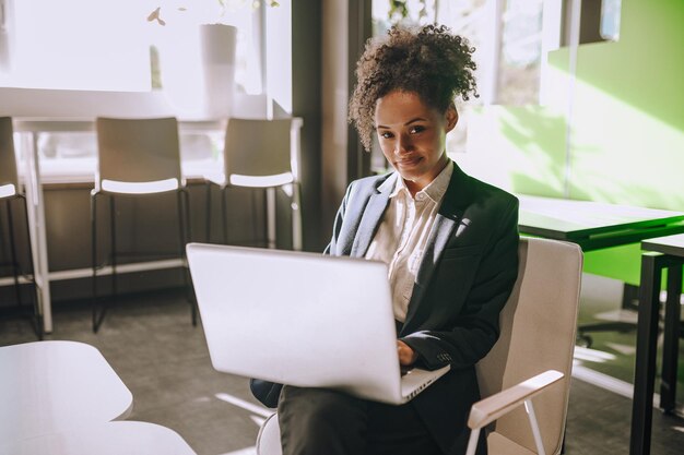 Woman working on laptop looking at camera