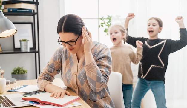 Foto donna che lavora su un computer portatile. bambini rumorosi e lavoro a distanza da casa.