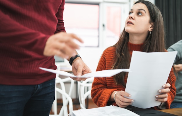 Woman working and listening to colleague at workplace.