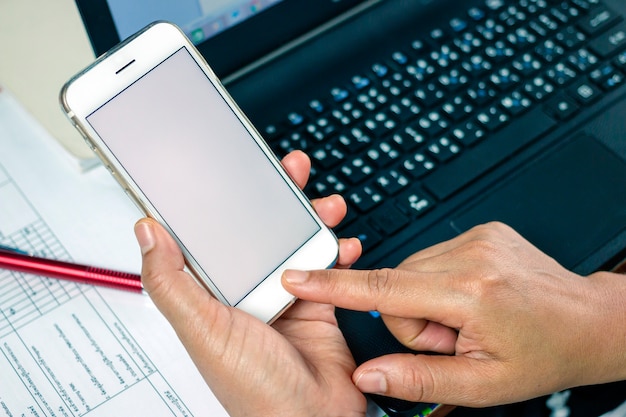 Woman working at office desk and texting with her mobile phone