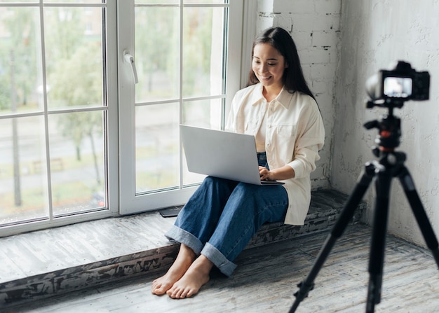 写真 新しいvlogのためにラップトップに取り組んでいる女性