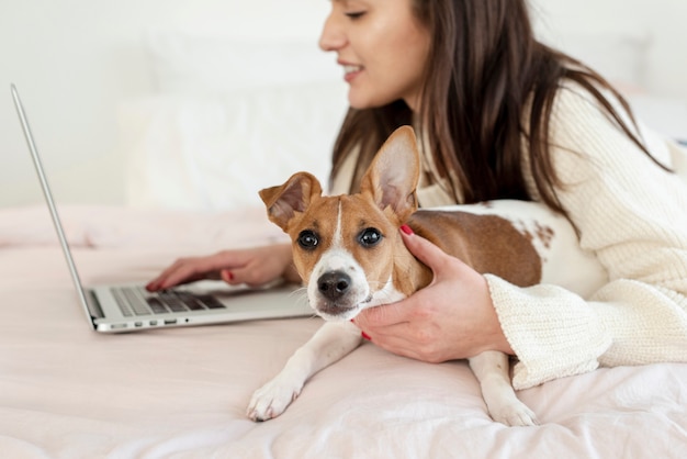 写真 彼女の犬と一緒にベッドでノートパソコンで働く女性