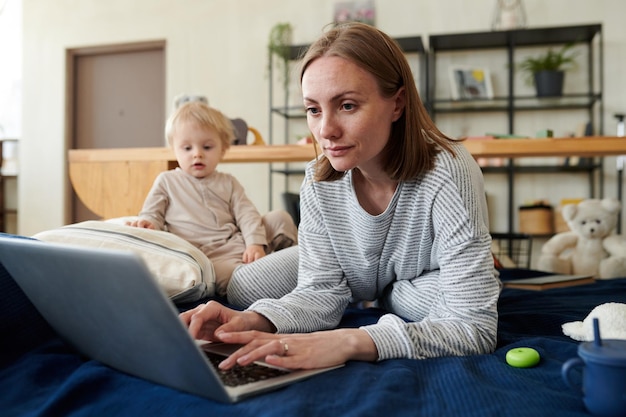 Woman working online on laptop with baby