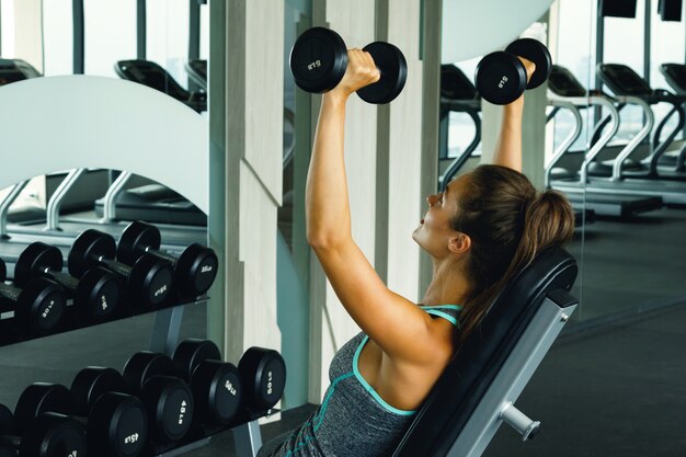 Woman working out with dumbbells in gym