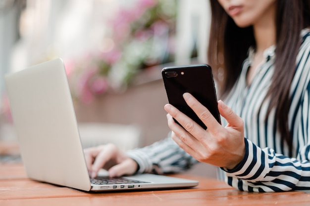 Woman working on phone and laptop 