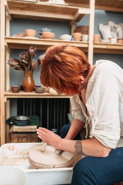 Woman working on potter wheel with clay