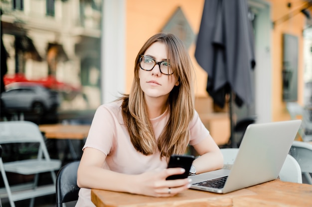 Woman working remotely with laptop and phone in cafe