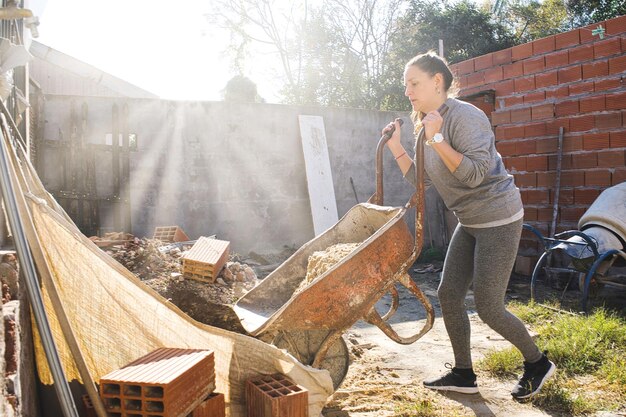 Woman working unloading sand from the wheelbarrow