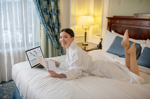 A woman working with a business report in her bedroom