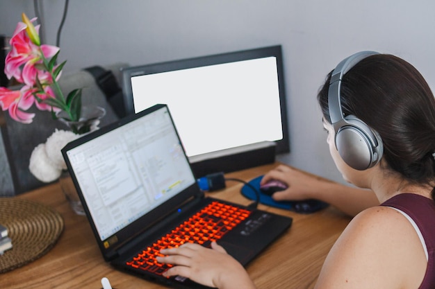 Woman working with her laptop from home listening to music with her headphones