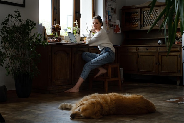 Woman working with laptop by window at home