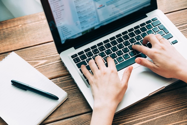 Woman working with laptop placed on the wooden desk