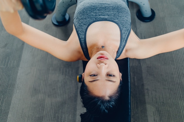 Woman workout for dumbbell bench press in the fitness gym.