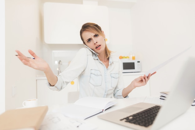 A woman works at home. She works on a laptop.