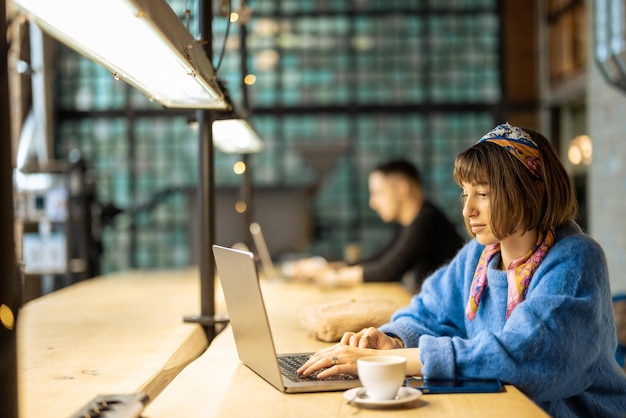 Photo woman works on laptop at coffee shop