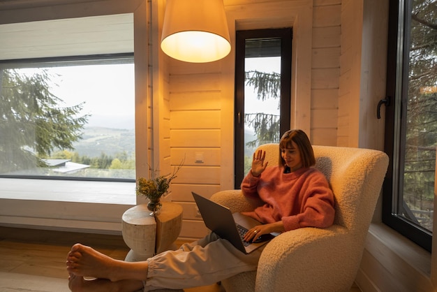 Photo woman works on laptop at house in mountains