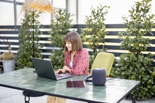 Женщина работает на ноутбуке онлайн в саду на открытом воздухе